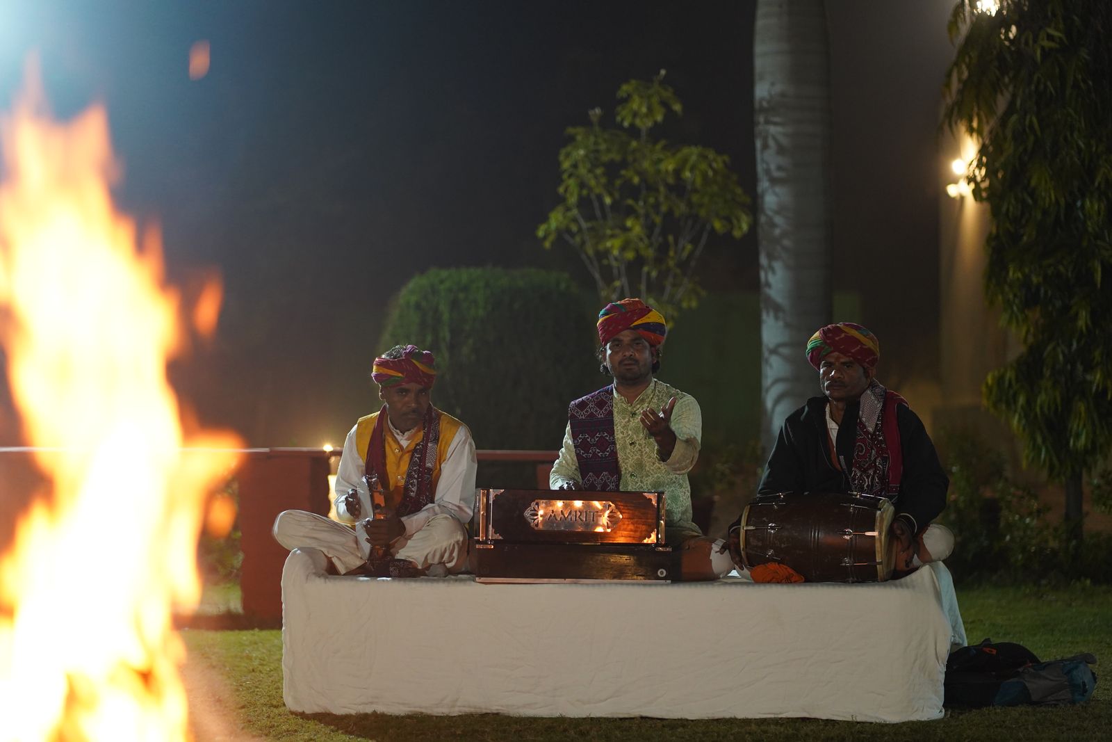 Folk musicians performing beside a campfire at night